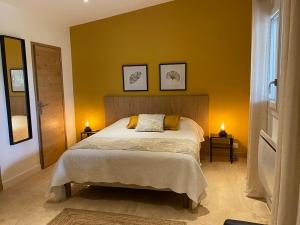 - une chambre dotée d'un lit avec un mur jaune dans l'établissement Domaine du Mas Foucray, aux Baux-de-Provence