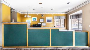 a lobby with a green counter and yellow walls at Cedar Valley Inn in Cedar City
