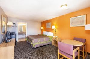 a hotel room with a bed and a desk and a table at Cedar Valley Inn in Cedar City +8 photos