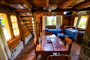 ein Esszimmer mit einem Holztisch in einer Blockhütte in der Unterkunft Complejo Flores Azules in Olta