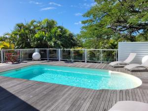 a swimming pool on top of a deck with chairs and aitures at VILLA STE MARTHE avec piscine, grande terrasse, jardin intime et citerne d'eau in Saint-François