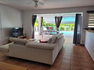 a living room with a white couch and a tv at VILLA STE MARTHE avec piscine, grande terrasse, jardin intime et citerne d'eau in Saint-François