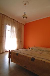 a bedroom with orange walls and a bed with a window at Haroula Apartments in Sidari