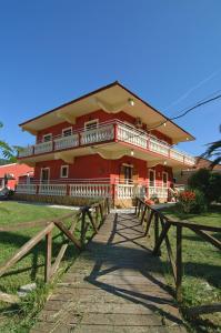 a red house with picnic tables in front of it at Haroula Apartments in Sidari