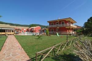 a large red house with a playground in front of it at Haroula Apartments in Sidari