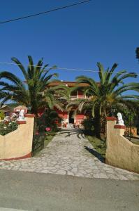 a street with palm trees in front of a building at Haroula Apartments in Sidari