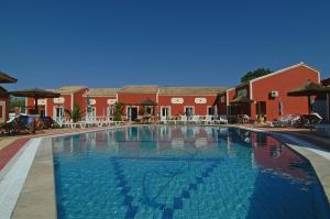 a large swimming pool in front of a red building at Haroula Apartments in Sidari