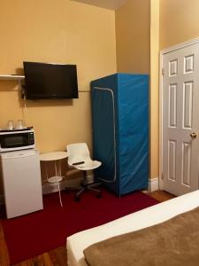 a room with a bed and a desk and a tv at Adas Guesthouse in Toronto