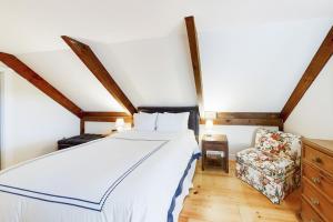 Un dormitorio con una cama blanca y una silla. en Appalachee Pond Waterfront Cottage, en Boothbay Harbor