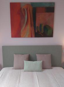 a painting above a bed with two pillows at Casa Fisher in Vendas Novas