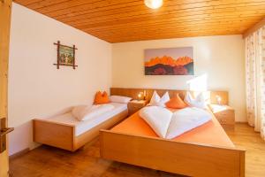 two beds in a room with wooden ceilings at Galreidhof in Funes