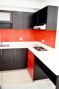 a kitchen with black cabinets and red tiles at Hotel Mare Apartasuite in Cali