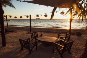 uma mesa e cadeiras numa praia com o oceano em Hotel Luna De Plata em Mahahual