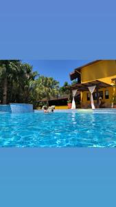 a pool at a resort with people in the water at Jardim Boêmio in Cananéia