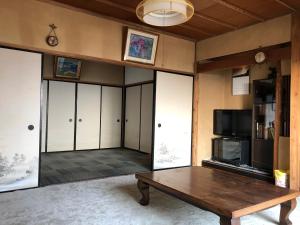 a living room with a wooden table and a tv at 伊豆海の家（Izu Seaside Villa） in Higashiizu