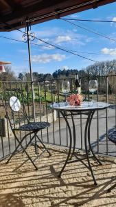 una mesa con 2 sillas y copas de vino en un porche en O fogar da musiña en Maside