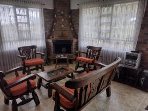 sala de estar con sillas y chimenea en Cabaña Villa Gabriela, en Paipa