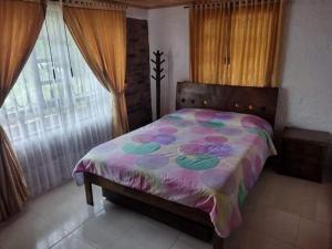 a bedroom with a bed with a colorful comforter at Cabaña Villa Gabriela in Paipa