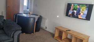 sala de estar con TV, sofá y mesa en Lovely 2-bedroom flat with free parking en Glasgow