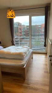 ein Schlafzimmer mit einem Bett und einem großen Fenster in der Unterkunft Appartement “zon en vakantie aan zee” in Koksijde