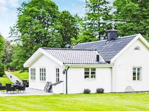 een wit huisje met een zwart dak bij Holiday home ÅSBRO III in Åsbro