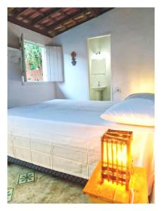 - une chambre avec un grand lit blanc et une fenêtre dans l'établissement Tropicália Hostel e Pousada, à Itacaré