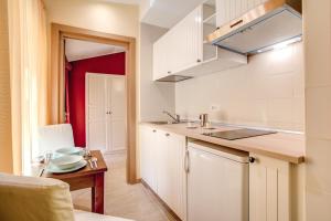 eine Küche mit weißen Schränken, einer Spüle und einem Tisch in der Unterkunft Top Floor Navona in Rom