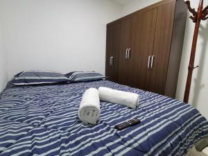 1 cama con toallas, un libro y un mando a distancia en Apartasuite Altos del Bosque, en Punta Arenas