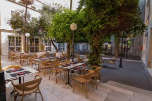 un patio al aire libre con mesas, sillas y árboles en San Gil, en Sevilla