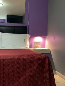 a bedroom with a red bed with a purple wall at Motel Las Dunas in Mexicali