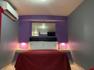 a bedroom with a bed with a purple wall at Motel Las Dunas in Mexicali