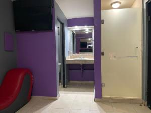 a bathroom with purple walls and a sink and a red chair at Motel Las Dunas in Mexicali
