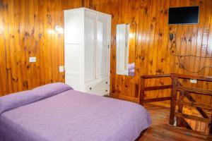 a bedroom with a bed and a wooden wall at Doña Margarita in Chascomús