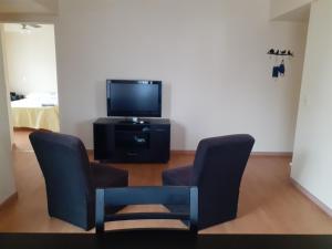 a living room with two chairs and a tv at Urquiza Tower Hermoso departamento con cochera in Buenos Aires