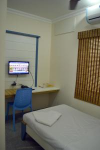 een slaapkamer met een bed en een bureau met een computer bij Metro Park in Chennai