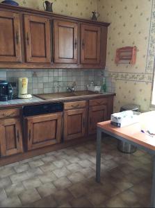 eine Küche mit Holzschränken und einem Tisch in der Unterkunft Maison champêtre au coeur de la campagne in Fontaines