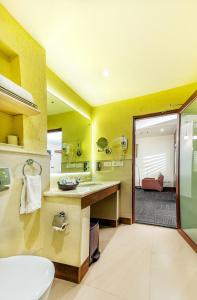 a bathroom with yellow walls and a sink and a shower at Flora Airport Hotel and Convention Centre Kochi in Nedumbassery