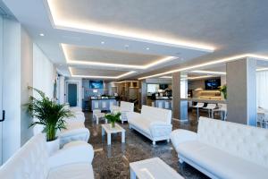 a living room with white couches and a kitchen at El Cid Campeador - Family Hotel in Rimini