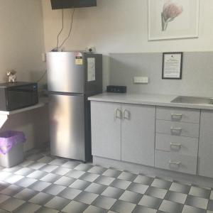 a kitchen with a refrigerator, sink, and dishwasher at Ayrline Motel in Ayr