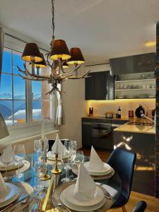 Wiler的住宿－Apartment Di Lembah，厨房配有玻璃桌、椅子和吊灯。