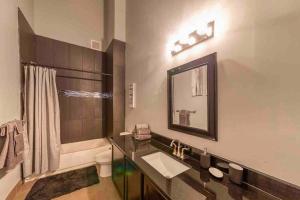 a bathroom with a sink and a toilet and a mirror at Detroit Skyline Luxe Loft 2-Bedroom w/2 Fireplaces in Detroit
