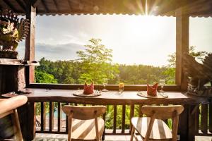 a table on a balcony with a view of the forest at Magatama Villa by Mahaputra in Gianyar