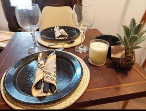 a wooden table with plates and wine glasses on it at La Boutique Aparts Temporarios Corrientes Pleno centro in Corrientes