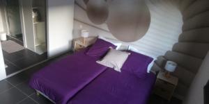 a bedroom with a purple bed and a mirror at 87620 la chambre du clos Barriant in Séreilhac