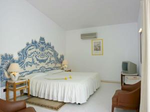 a blue and white bedroom with a bed and two chairs at Hotel Apartamento Do Golfe in Vilamoura