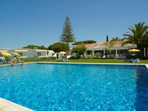 a large blue swimming pool in front of a house at Hotel Apartamento Do Golfe in Vilamoura