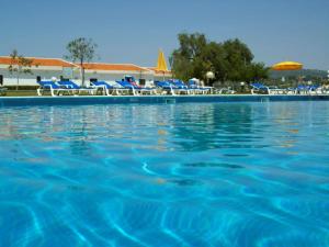 a large swimming pool with chairs and an umbrella at Hotel Apartamento Do Golfe in Vilamoura