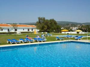 a large swimming pool with chairs and umbrellas at Hotel Apartamento Do Golfe in Vilamoura