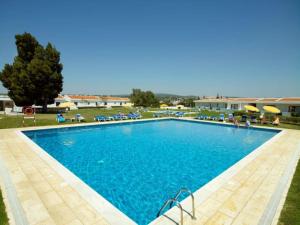 a large blue swimming pool with chairs and umbrellas at Hotel Apartamento Do Golfe in Vilamoura