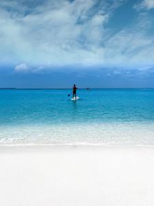 una persona de pie en una tabla de surf en el océano en Blue Coral Vashafaru Maldives, en Vashafaru